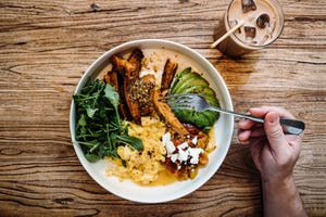 flat lay shot of man having healthy vegan green salad bowl for brunch in cafe table top view of a man eating breakfast with a glass of iced latte sitting at wooden dining table healthy eating lifestyle people, food and lifestyle concept