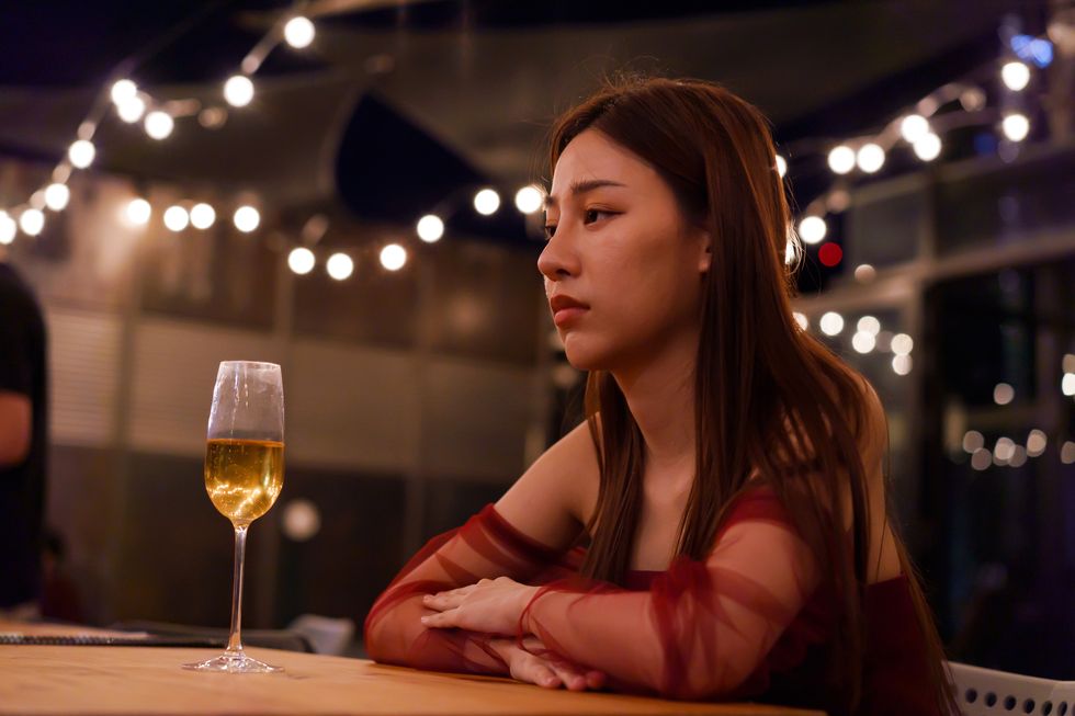 young asian woman feeling sad and heartbroken after breaking up with her boyfriend while sitting at restaurant