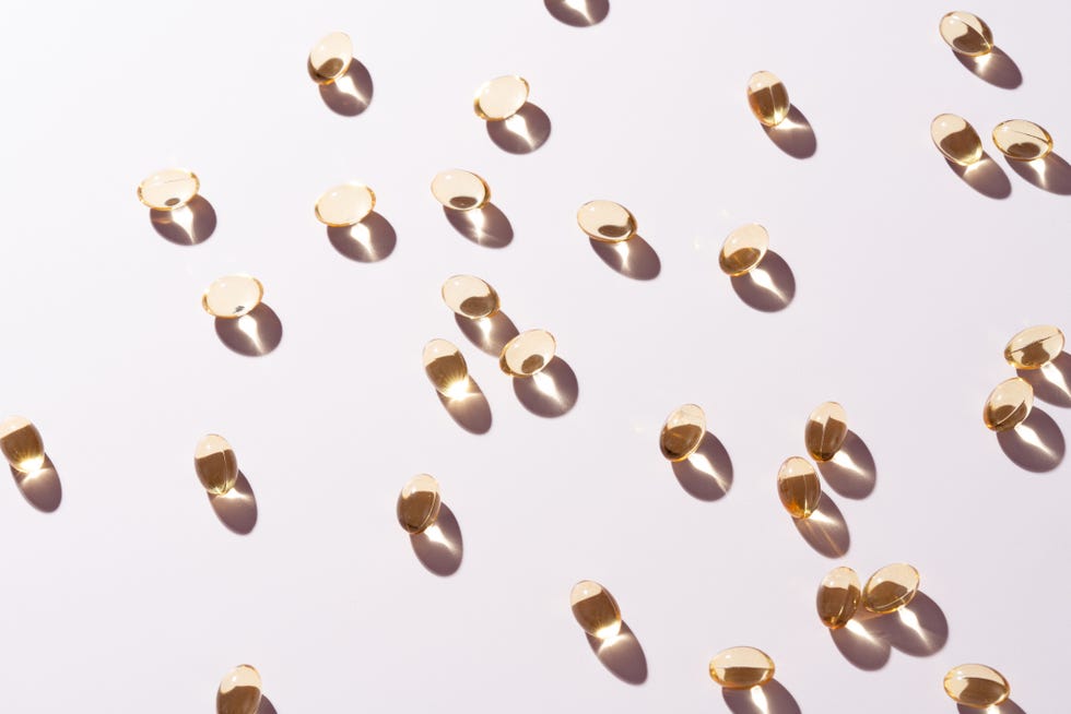 gold colored soft capsules of nutritional supplement on pink background high angle view