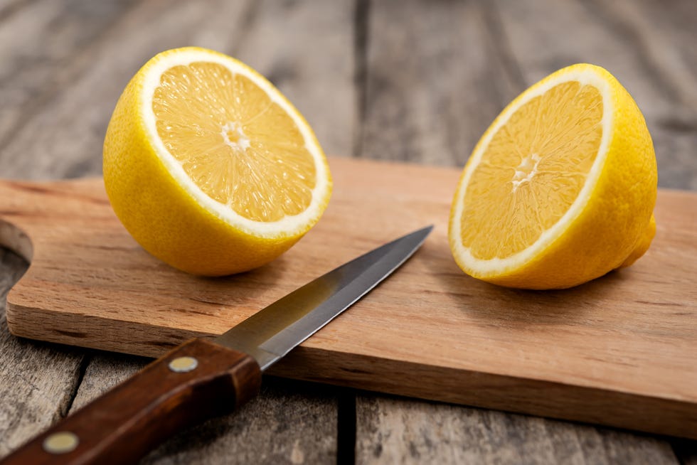 fresh lemon cut in half with knife on wooden cutting board