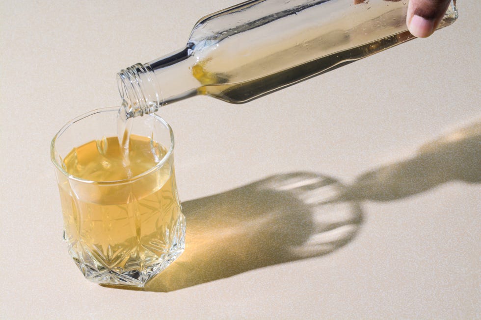 pouring apple cider vinegar in a glass cup