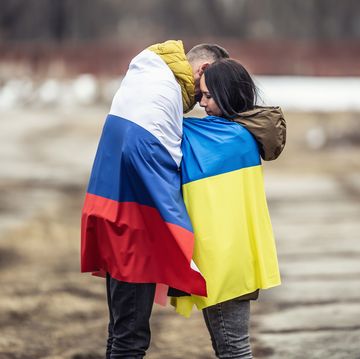 symbol of peace between russia and ukraine as young couple hugs dressed in their national flags