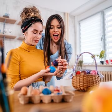 two beautiful young women sitting at home and playing an egg tapping game with easter eggs for easter