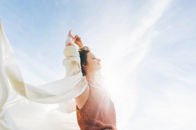 dreamy portrait of a young woman against the blue sky feeling full of confidence