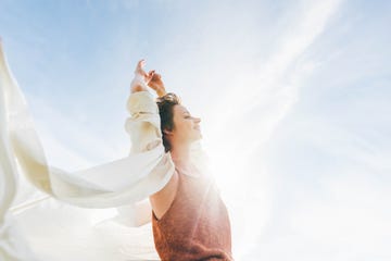 dreamy portrait of a young woman against the blue sky feeling full of confidence