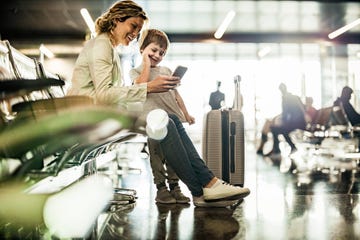 happy mother and her small son using smart phone while waiting for their flight at departure area