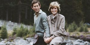 prince charles and princess diana stand in a field near a river and hold hands, both smile