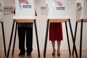 two individuals stand behind voting booths