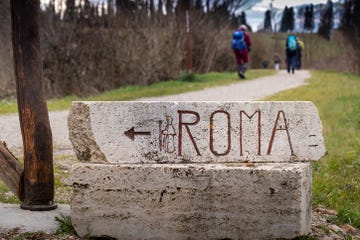 stone signs towards rome on the via francigena, departure from siena to ponte darbia plowed fields and cereal hills with solitary trees, conclusion of the route along the via cassia tuscany, italy