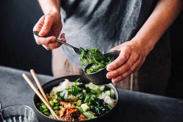 close up of woman eating omega 3 rich salad female having healthy salad consist of chopped salmon, spinach, brussels sprouts, avocado, soybeans, wakame and chia seeds in a bowl