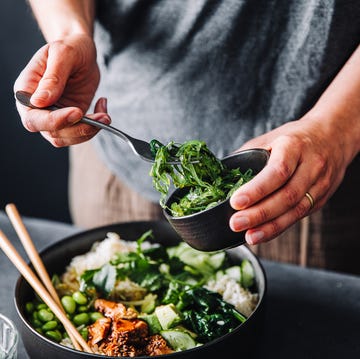 Close-up of woman eating omega 3 rich salad close up of woman eating omega 3 rich salad female having healthy salad consist of chopped salmon, spinach, brussels sprouts, avocado, soybeans, wakame and chia seeds in a bowl