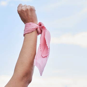 Close up shot of a female cancer patient's hand with a pink scarf tied to her wrist. Concept of fighting and beating cancer. close up shot of a female cancer patient's hand with a pink scarf tied to her wrist. concept of fighting and beating cancer.