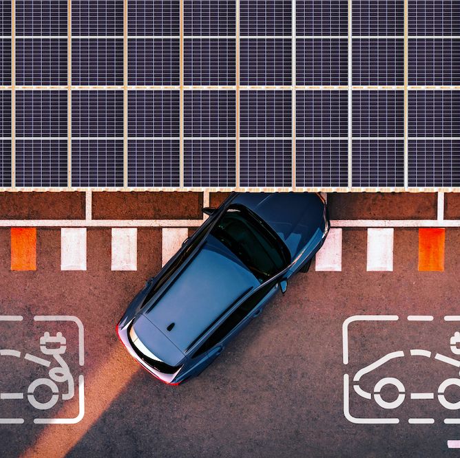 directly above view taken with drone of a charging station for electric and hybrid cars using solar panels to generate electricity to charge cars battery while are parked in the city