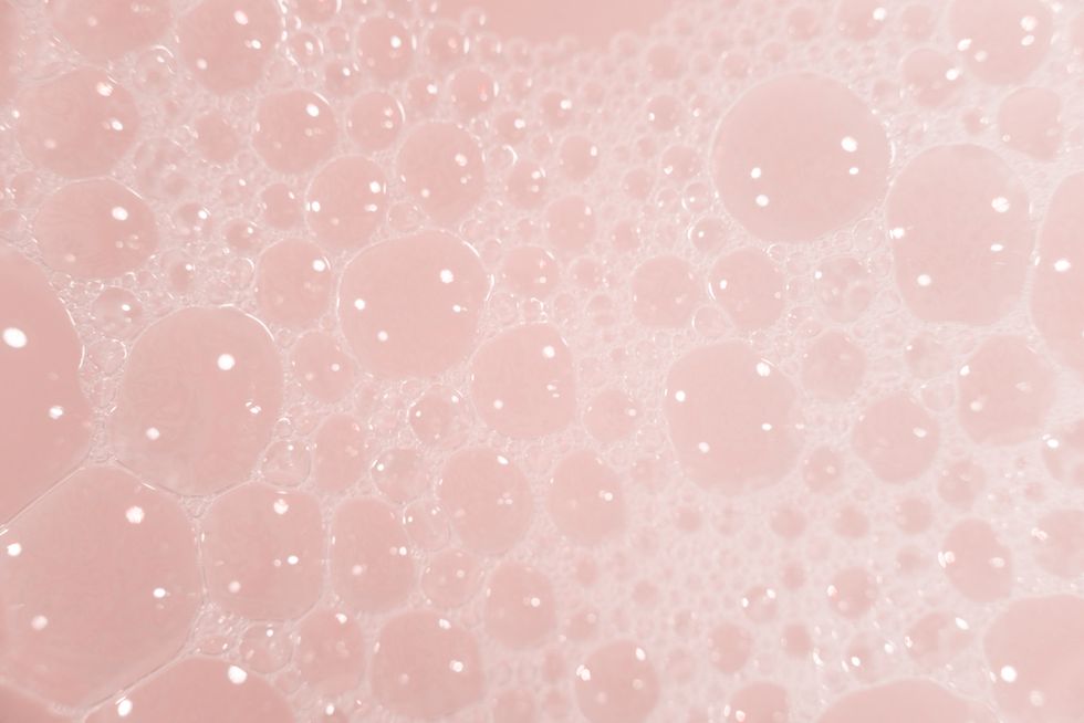 texture of white cosmetics foam texture on pink background cleanser, shampoo bubbles, wash liquid soap, shower gel, shampoo