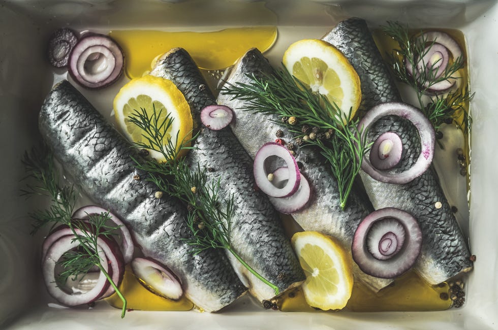 pickled whole herring with lemon, red onion, dill and oil. preparing delicious fish dish at home with ingredients. top view.