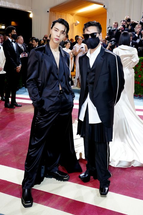 johnny suh, in a loose black suit with a long jacket and steel tipped boots, and peter do, in a black suit with an oversize white button down and a black face mask, attend the met gala in 2022