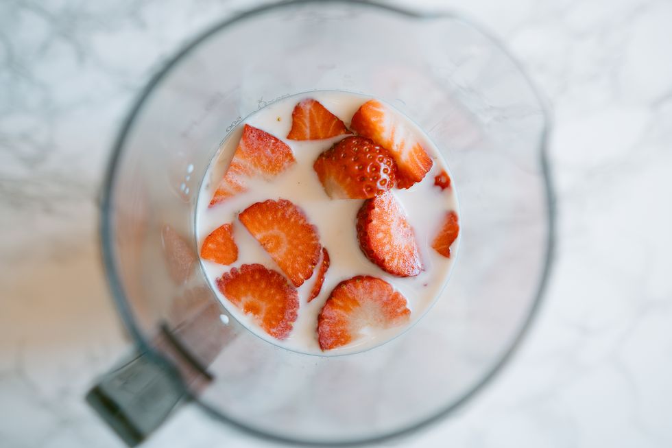 high angle view of milk and sliced strawberries inside a jug to make a strawberry milkshake