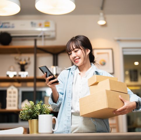 beautiful young woman with smartphone receiving parcel purchased online