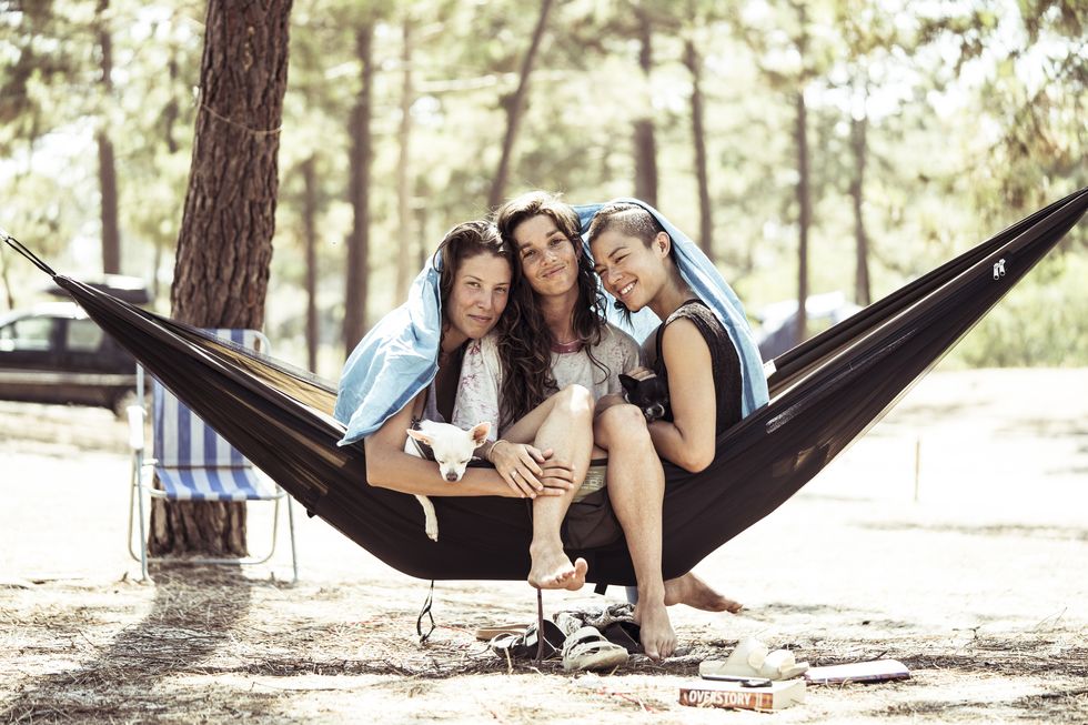 a group of women sitting in a hammock in the woods