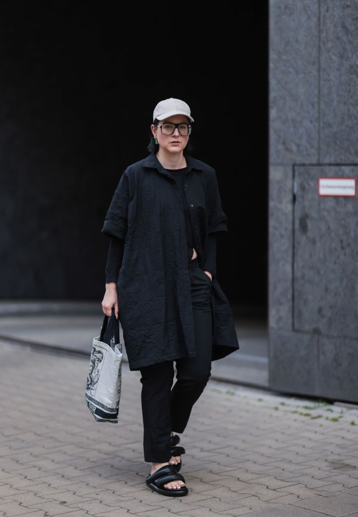 dusseldorf, germany june 12 maria barteczko seen wearing a beige arket linen baseball cap, a black oversized aviator glasses from victoria beckham, black short sleeve oversized shirt from wendykei, a black asymmetric top from wendykei, black classic straight pants from wendykei, a beige logo canvas tote bag from dior and black zuzzuiz padded leather sandals on june 12, 2022 in dusseldorf, germany photo by jeremy moellergetty images