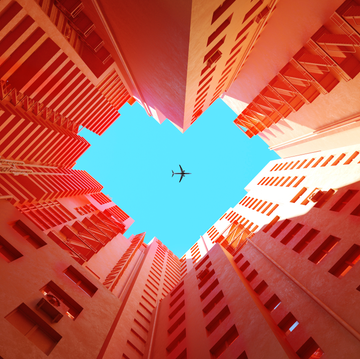 digital generated image of orange buildings making heart shape with airplane flying on blue sky