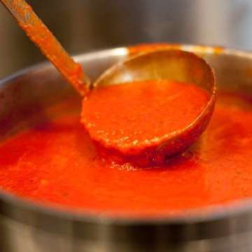 Ladle in pot of marinara sauce a ladle scooping a rich tomato sauce from a pot