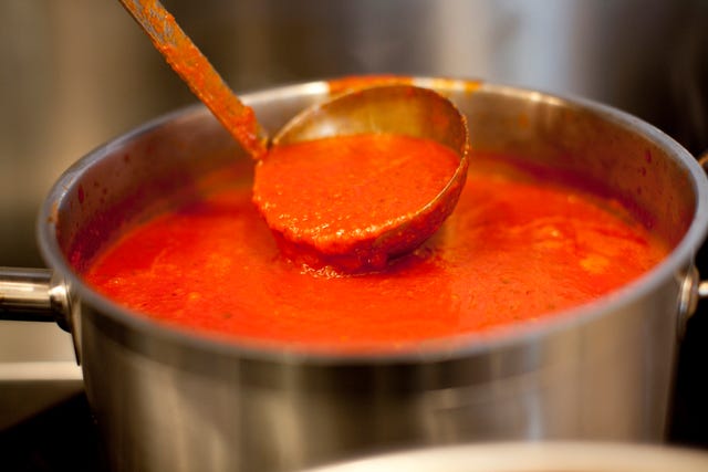 ladle dipping into a pot of red sauce