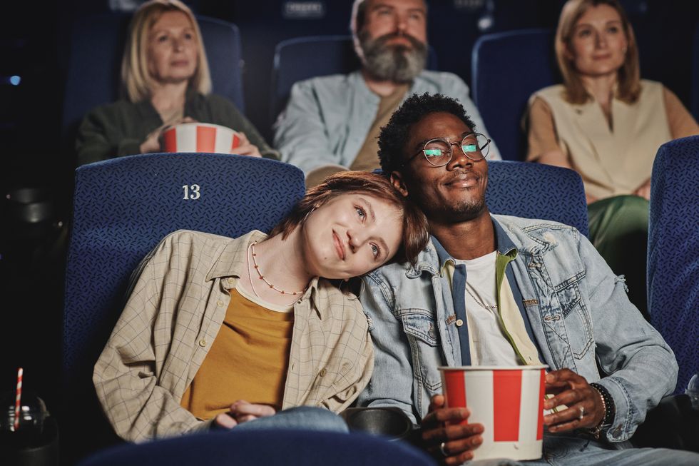 portrait of modern lovey dovey ethnically diverse young couple spending evening on date at cinema