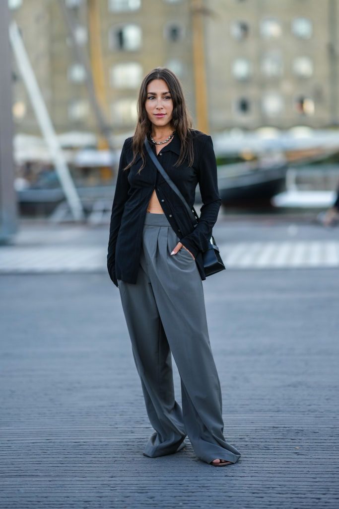 copenhagen, denmark august 11 a guest wears a gold large chain necklace, a black buttoned long cardigan, a black shiny leather crossbody bag, dark gray wide legs suit pants, dark brown shiny leather heels sandals, outside ganni, during copenhagen fashion week springsummer 2023, on august 11, 2022 in copenhagen, denmark photo by edward berthelotgetty images