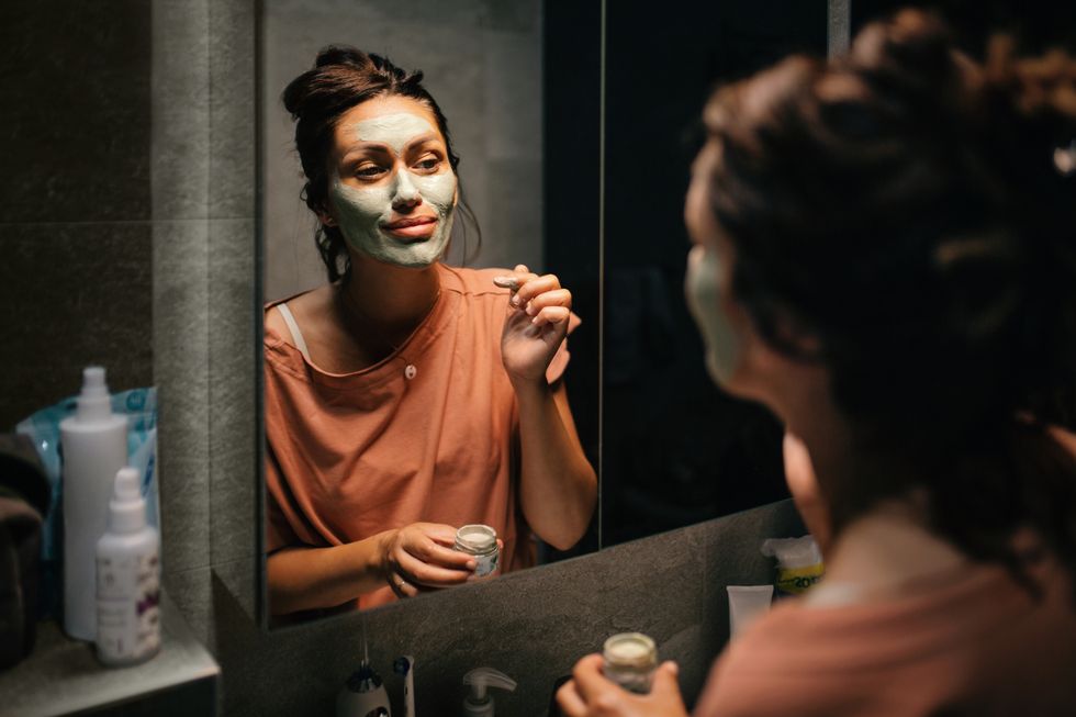 woman applying a facial clay mask to her face in the bathroom its one of her bedtime routines