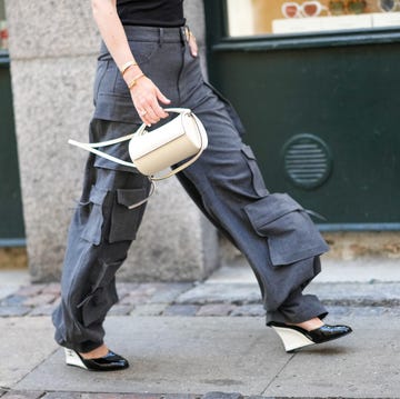 Street Style - Day 3 - Copenhagen Fashion Week Spring/Summer 2023 copenhagen, denmark august 11: annabel rosendahl wears a black turtleneck / shoulder off / sleeveless / body top, dark gray large cargo pants, a gold watch, gold rings, gold love bracelet from cartier, a gold juste un clou bracelet from cartier, a white matte leather tube handbag, black shiny varnished leather pointed with white wedge heels shoes from chanel, outside mark kenly domino tan during copenhagen fashion week spring/summer 2023, on august 11, 2022 in copenhagen, denmark. (photo by edward berthelot/getty images)