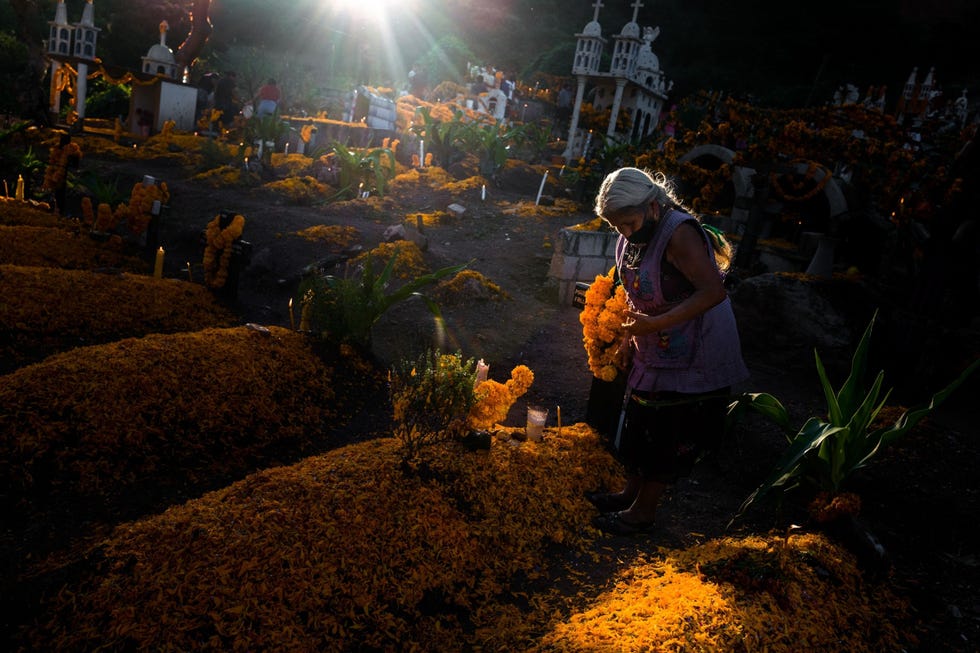 Een Mixteekse vrouw versiert op 2 november 2021 tijdens Da de los Muertos een graf op een begraafplaats in Xalpatlhuac in Mexico
