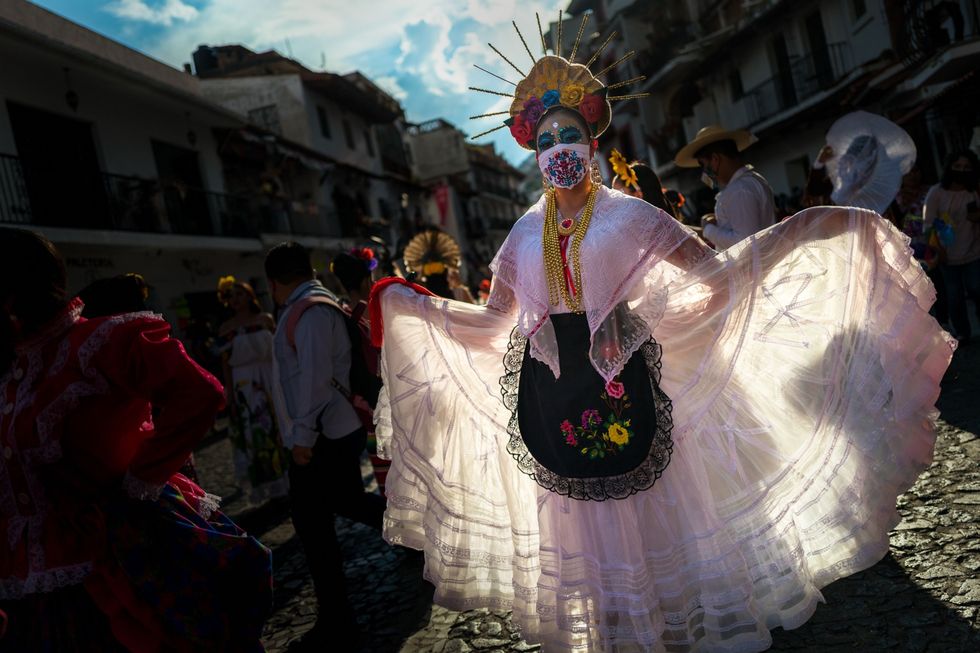 Een jonge Mexicaanse die zich heeft verkleed als la Catrina en een geborduurd mondkapje draagt treedt op 29 oktober 2021 op tijdens een viering ter ere van Da de los Muertos in de Mexicaanse plaats Taxco de Alarcn