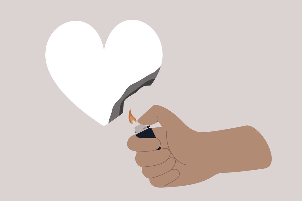 a hand burning a paper heart with a lighter, relationship difficulties