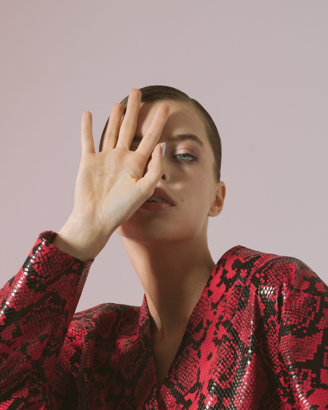 young fashion woman hand near face in red coat, close up studio portrait