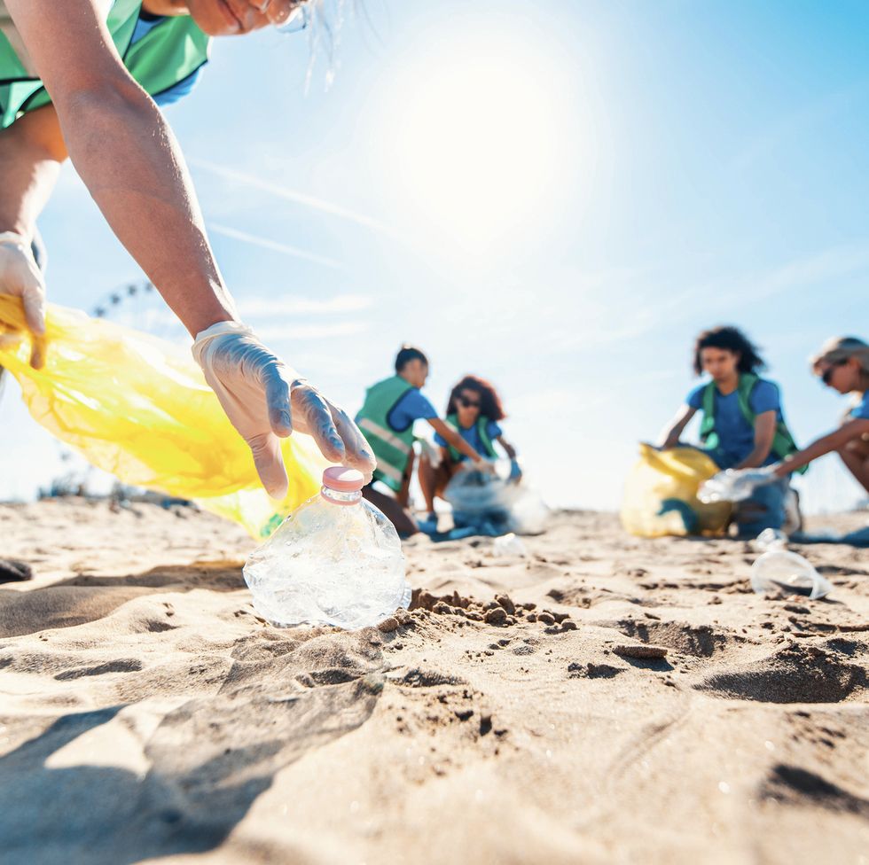 group of eco volunteers picking up plastic trash on the beach activist people collecting garbage protecting the planet ocean pollution, environmental conservation and ecology concept