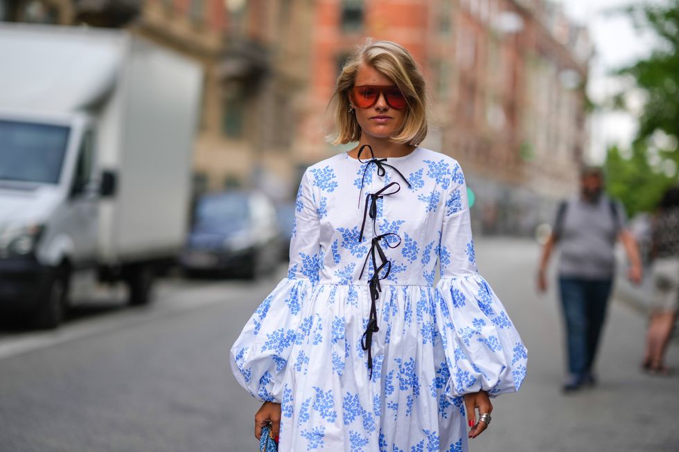 copenhagen, denmark august 09 a guest wears red sunglasses, silver earrings, a white with blue print pattern long puffy sleeves midi dress with black laces neck, silver rings , outside raeburn, during copenhagen fashion week springsummer 2023, on august 09, 2022 in copenhagen, denmark photo by edward berthelotgetty images