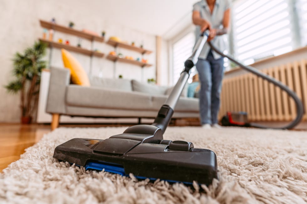 beautiful senior woman vacuuming the carpet in her apartment close up