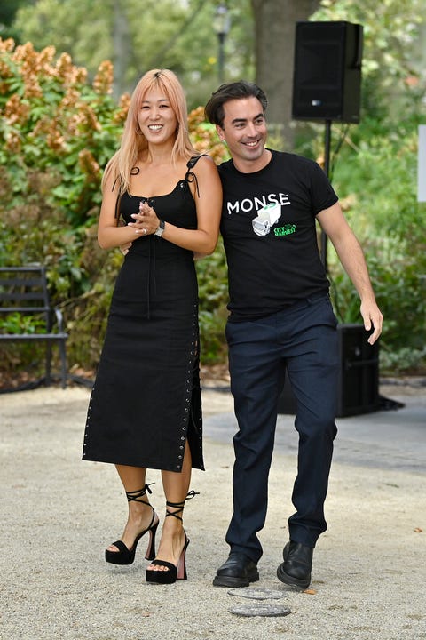 monse designers laura kim, in a black dress with grommets down the side and platform sandals, and fernando garcia, in a monse t shirt and navy trousers, at an outdoor fashion show