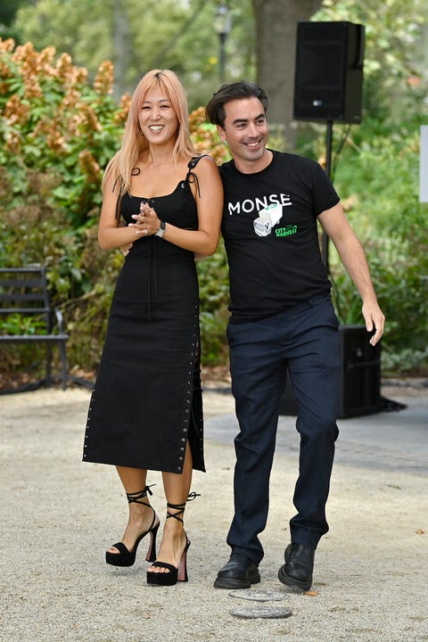 Laura Kim and Fernando Garcia of Monse monse designers laura kim, in a black dress with grommets down the side and platform sandals, and fernando garcia, in a monse t shirt and navy trousers, at an outdoor fashion show