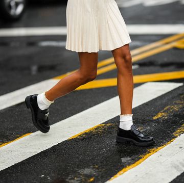 new york, new york september 11 a guest wears a white latte embossed ribbed short skirt, white socks, black shiny varnished leather loafers from prada, gold and silver rings, outside khaite, during new york fashion week, on september 11, 2022 in new york city photo by edward berthelotgetty images