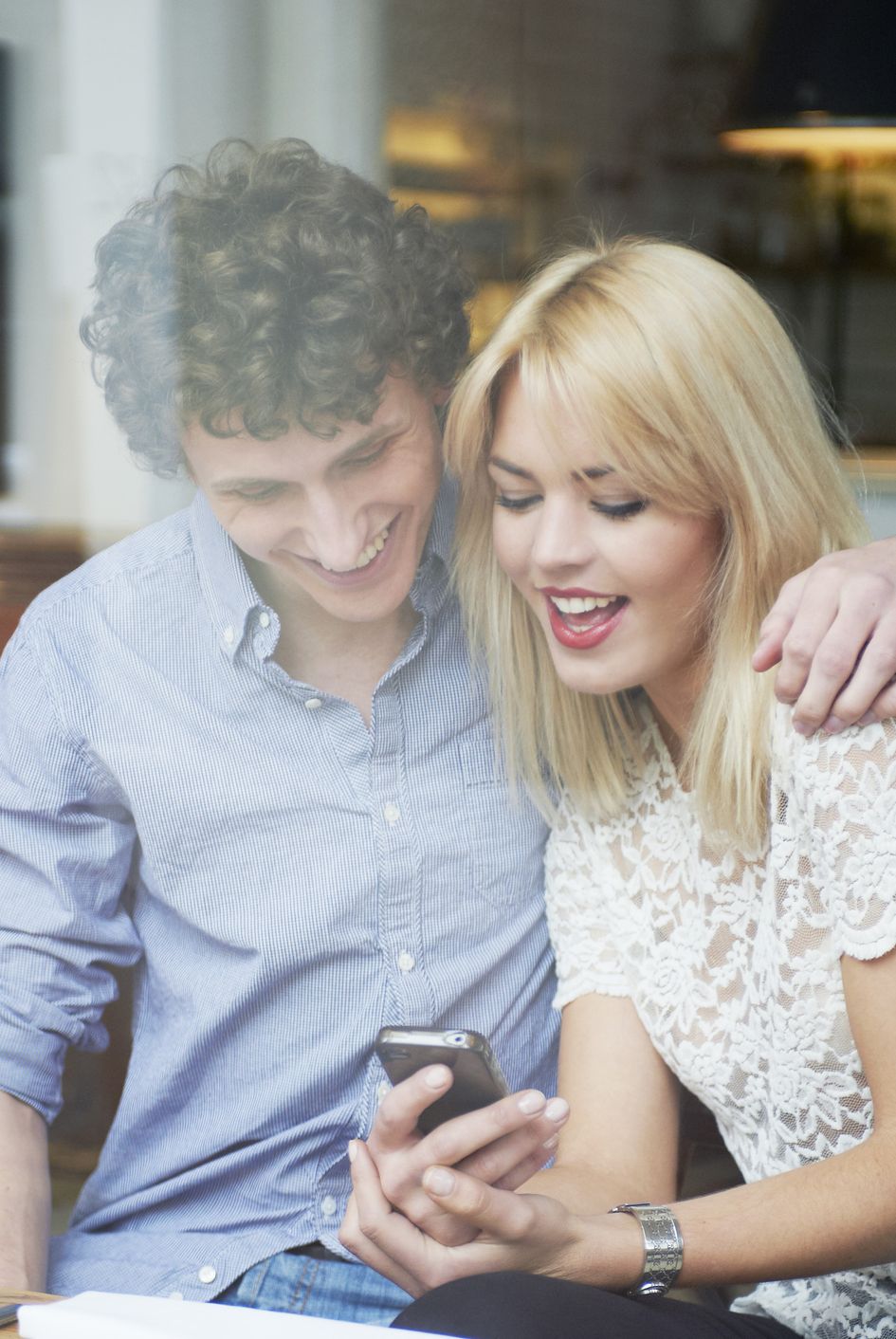 man and woman hugging and looking at mobile phone