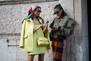 milan, italy september 21 melanie darmon r wears a gold hair clip, black sunglasses, gold earrings, a brown with blue and red checkered print pattern oversized jacket, a red black white embroidered wool pattern knees skirt, gabriella berdugo l wears a red blue white print pattern silk scarf on the head, black sunglasses, silver earrings, gold necklaces, a yellow shoulder off short dress, a pale yellow jacket, a pale yellow and white tweed crossbody bag from chanel, outside alberta ferretti, during the milan fashion week womenswear springsummer 2023 on september 21, 2022 in milan, italy photo by edward berthelotgetty images