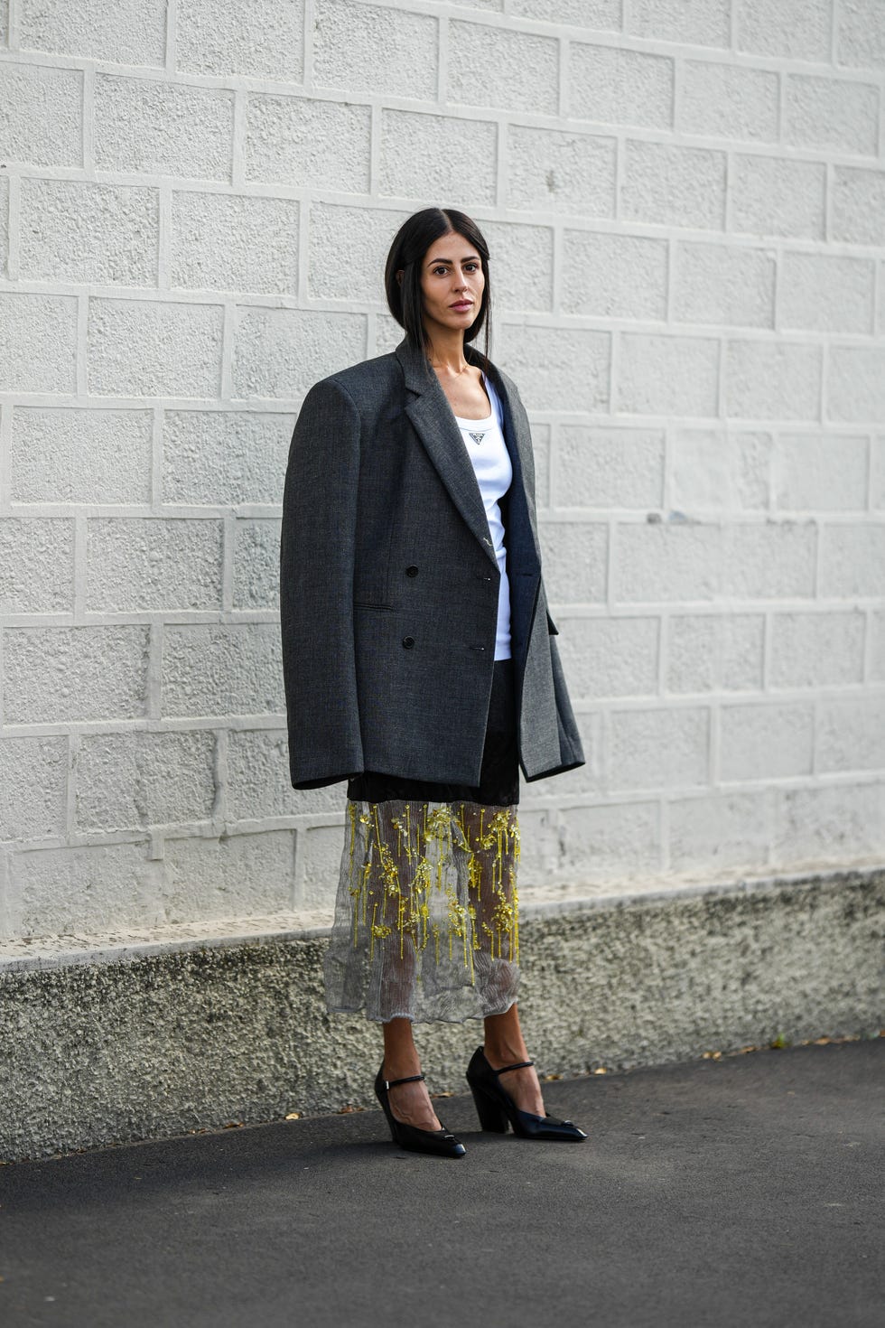 an oversized gray double breasted blazer is layered over a fitted white tank top