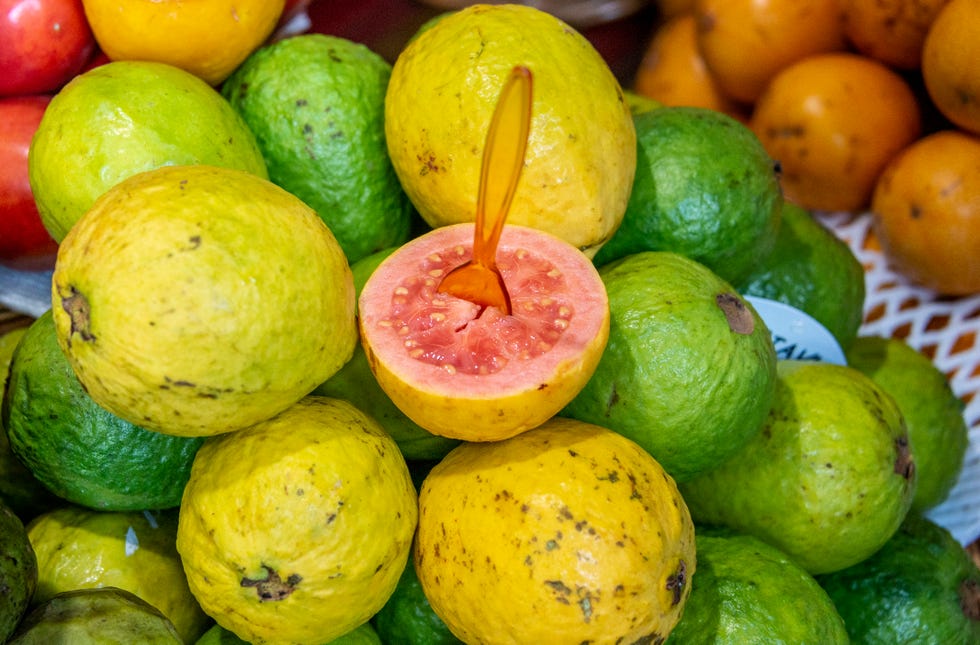 closeup of a red guava cut in half, in the background several guavas, madeira, portugal