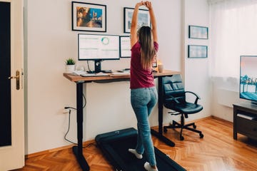 woman working from home at standing desk is walking on under desk treadmill