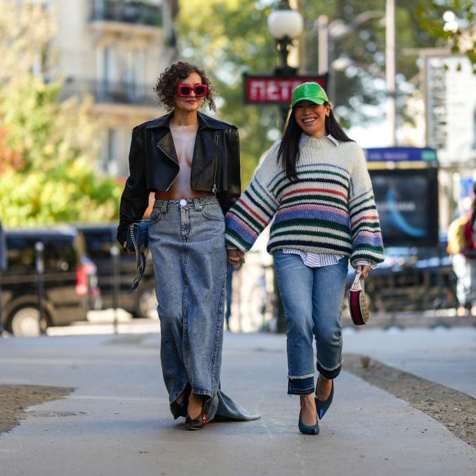 paris, france september 30 renia jaz wears red puffy sunglasses from loewe, a black shiny leather cropped jacket, a white and beige body print pattern body top, a dark gray denim long skirt, a blue denim handbag, black shiny leather pointed shoes with a large red circle heels  miki cheung wears green shiny varnished leather cap, a white with small black striped print pattern shirt, a white latte with red  green  blue striped print pattern oversized wool pullover, blue denim ripped ankle pants, a white leather with brown and beige gg monogram print pattern fabric handbag from gucci, blue and green tweed pointed pumps heels shoes, outside loewe, during paris fashion week womenswear springsummer 2023, on september 30, 2022 in paris, france photo by edward berthelotgetty images