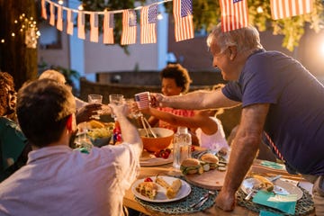 a multi generation multiracial family having dinner outdoors on an american national holiday