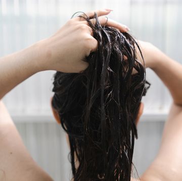 white woman washing her hair and taking a shower in the bathroom, view from behind