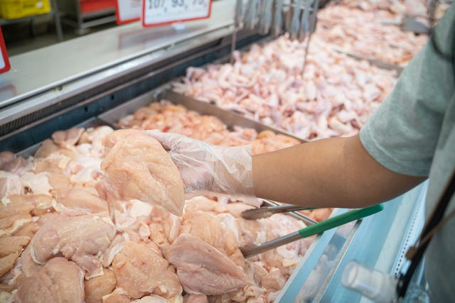 asian women shopping for fresh chicken meat at the supermarket.